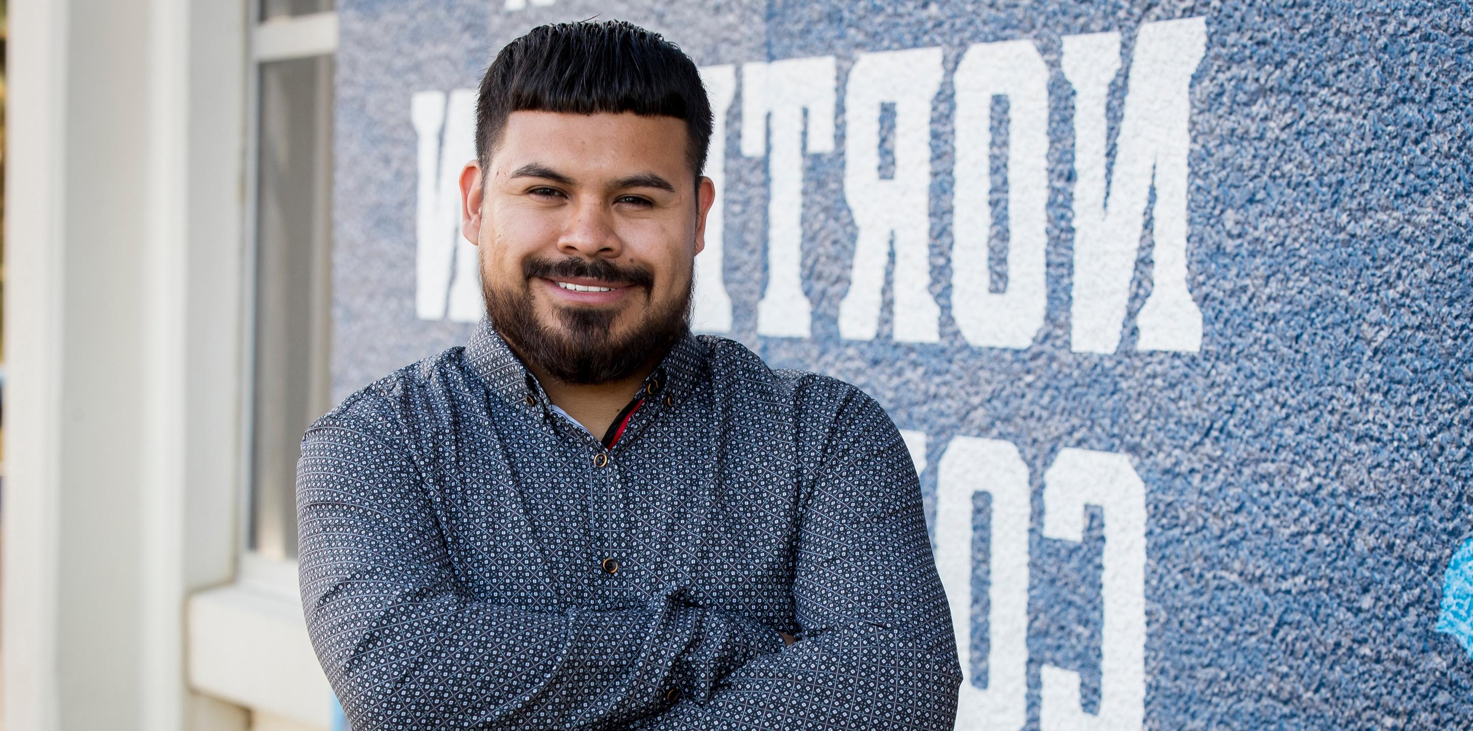 Fernando Beltrán parado junto a la pared con los brazos cruzados, sonriendo